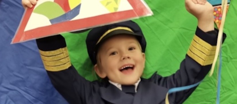 Boy dressed up for carnival laughs at camera while holding up a sign